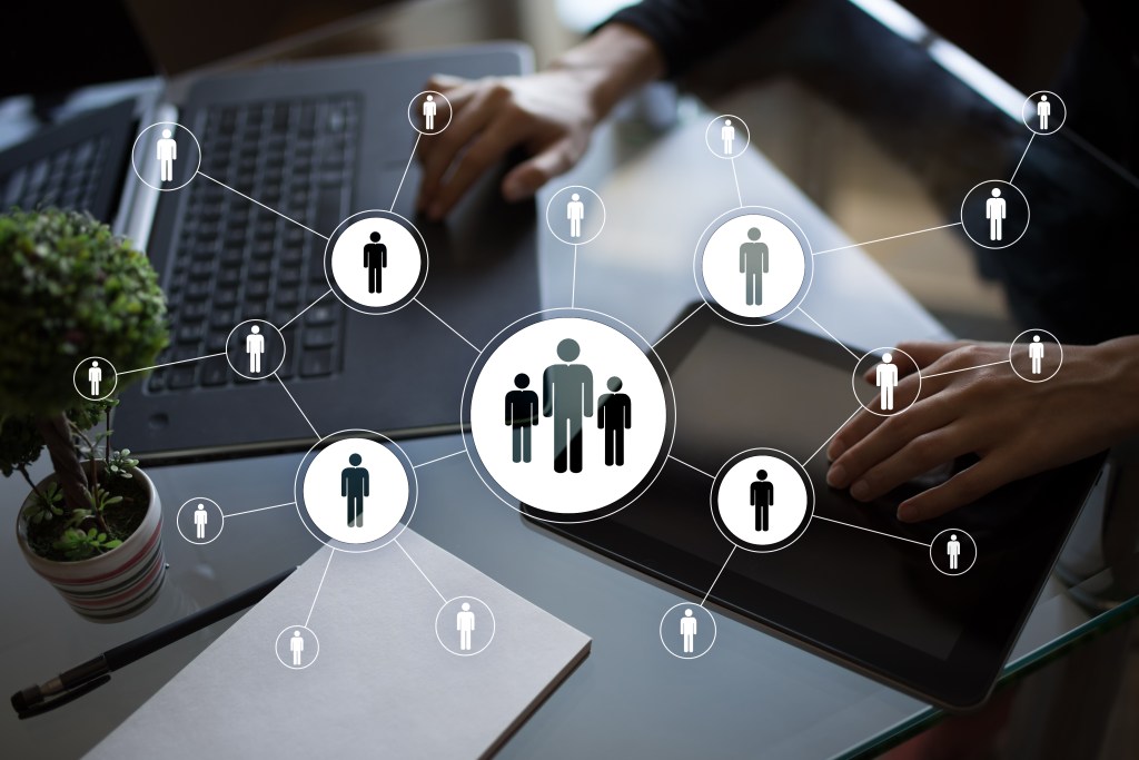 a man using a laptop with an icon of connected people connected in front