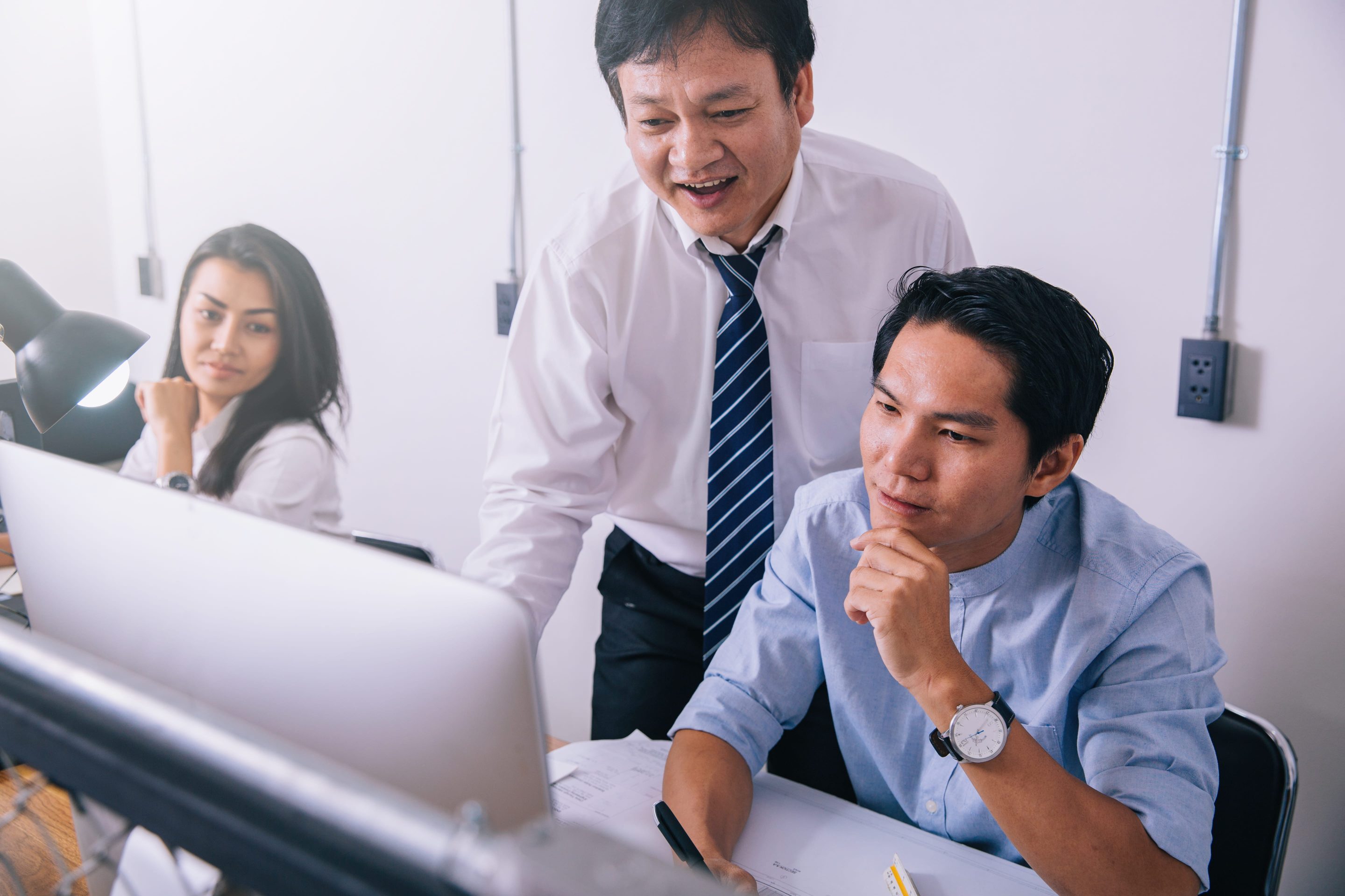 three working individuals looking at a laptop