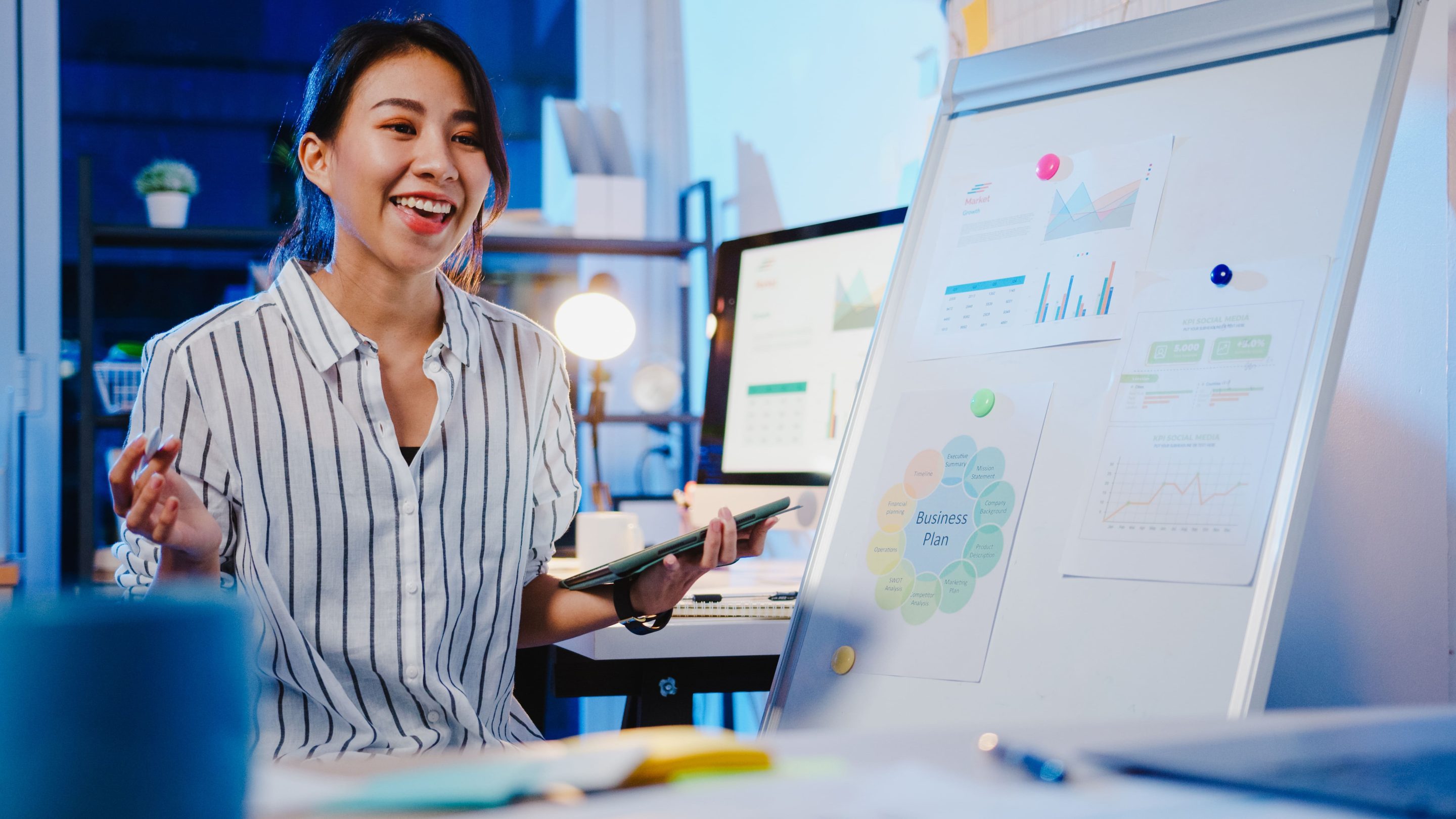 Young businesswoman presenting a business plan and analytics charts on a whiteboard