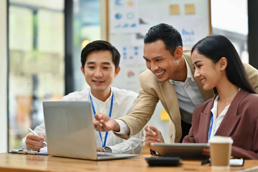 Business professionals collaborating on a laptop while planning CRM integration and workflow automation solutions