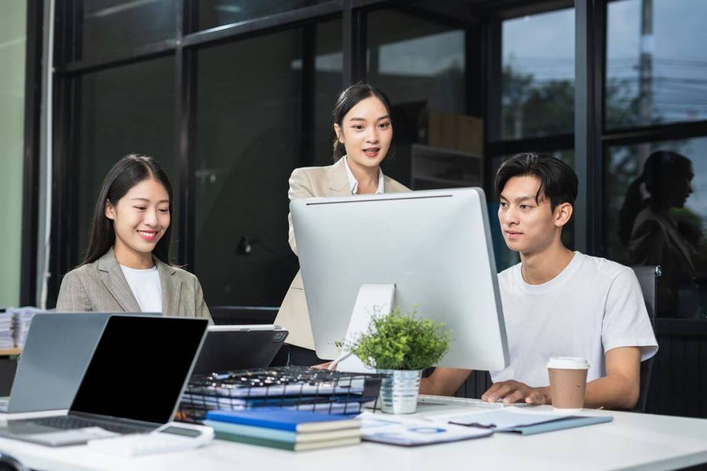 Business professionals collaborating at computers, representing Zia AI assisting teams across Zoho applications