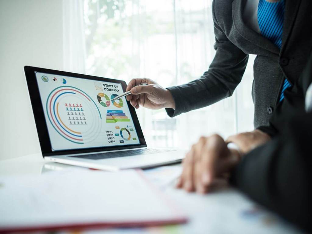 Business professional presenting performance data on a laptop, illustrating how Odoo connects CRM and ERP through shared business records