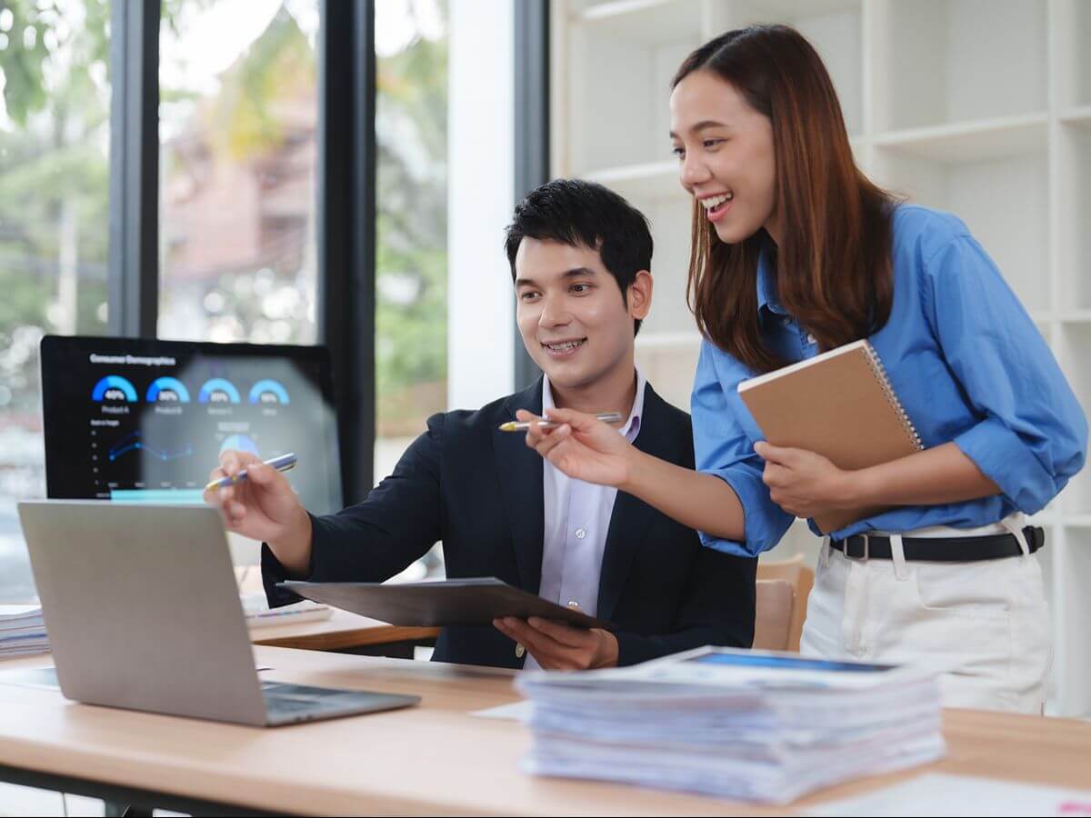 Business professionals reviewing analytics on a laptop, representing integrated CRM and ERP operations in Odoo
